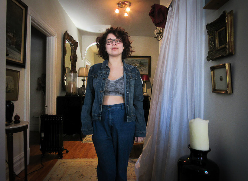 Model is facing the camera wearing a dark jean jacket with no daisies. The jacket reaches her hips. This is the before picture.